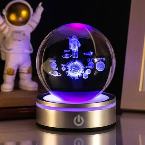 Palla di cristallo con rappresentazioni luminose di pianeti e astronauta, ideale come decorazione scientifica o oggetto da collezione.