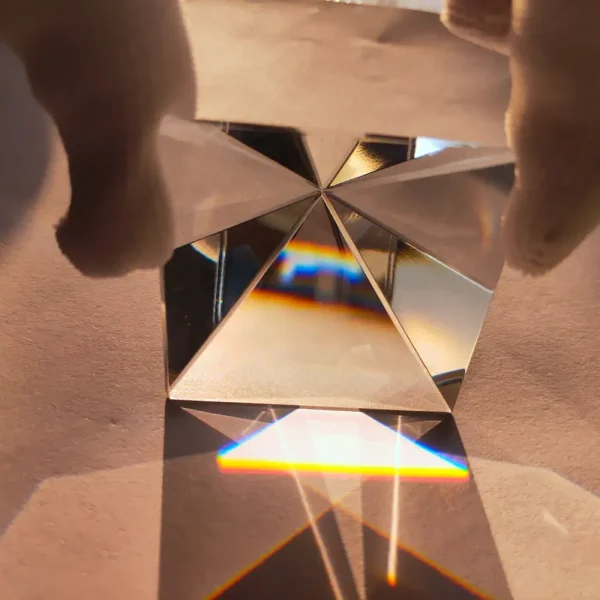 Prisma di cristallo con riflessi di luce e arcobaleni, oggetto decorativo scientifico, mostra effetti ottici e rifrazione della luce.