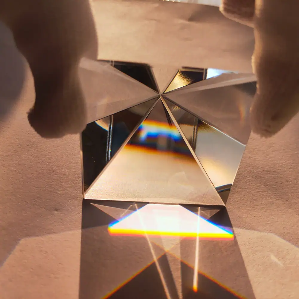 Prisma di cristallo con riflessi di luce e arcobaleni, oggetto decorativo scientifico, mostra effetti ottici e rifrazione della luce.