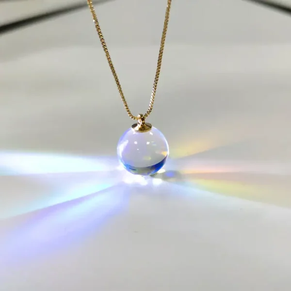 Pendente in vetro trasparente con effetto arcobaleno, sospeso su una delicata catena dorata, crea riflessi di luce colorati. Perfetto come gioiello decorativo e oggetto scientifico artistico.