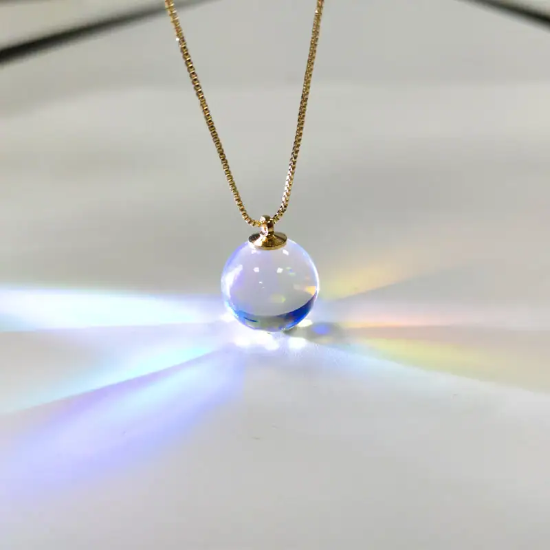 Pendente in vetro trasparente con effetto arcobaleno, sospeso su una delicata catena dorata, crea riflessi di luce colorati. Perfetto come gioiello decorativo e oggetto scientifico artistico.