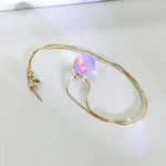 Collana con pendente sferico iridescente e catena dorata, perfetta come decorazione scientifica o accessorio di moda. Design elegante e moderno, ideale per appassionati di scienza e stile.