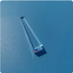 Penna di vetro colorata con effetto arcobaleno, posizionata su una superficie blu, ideale come decorazione scientifica o oggetto da collezione.