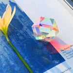 Palla di cristallo iridescente su sfondo blu e foglio di carta con testo.
