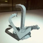 Gancio di sollevamento a forma di C in metallo, utilizzato in ambito scientifico e industriale per il sollevamento e la movimentazione di oggetti pesanti. Design robusto e funzionale, ideale per decor.