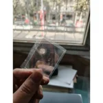 Piccolo oggetto scientifico trasparente in plastica, tenuto tra le dita, con sfondo di finestra e scrivania. Ideale per decorazioni o esperimenti scientifici.