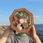 Oggetto decorativo in legno e resina con elementi naturali come foglie e pietre, ideale come decorazione scientifica o regalo originale.