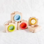 Fotocamera giocattolo in legno con obiettivi colorati, perfetta come decorazione scientifica o giocattolo educativo per bambini, in stile naturale e colorato.