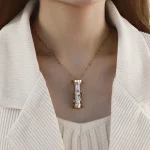 Collana decorativa con pendente cilindrico in vetro e dettagli metallici, indossata da una donna con abbigliamento chiaro, perfetta per appassionati di oggetti scientifici e design innovativo.