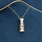 Collana con pendente cilindrico decorato con dettagli scientifici dorati e cristalli, perfetta come gioiello ispirato alla scienza.