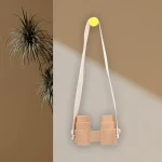 Binocolo decorativo in legno appeso alla parete con corda bianca e puntina gialla, perfetto come oggetto scientifico decorativo per ambienti educativi o moderni.