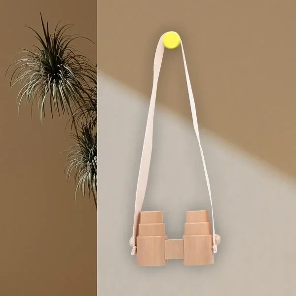 Binocolo decorativo in legno appeso alla parete con corda bianca e puntina gialla, perfetto come oggetto scientifico decorativo per ambienti educativi o moderni.