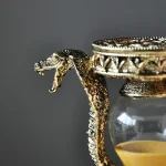 Serpente in metallo dorato con testa dettagliata avvolto attorno a un contenitore in vetro, perfetto come decorazione scientifica o oggetto da collezione.