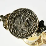 Pendente in metallo con simbolo del serpente e nodo celtico, dettagliato e decorativo, perfetto come oggetto decorativo o simbolico.