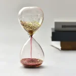 Orologio a clessidra decorativa con glitter dorato, simbolo di tempo e eleganza, perfetto come oggetto di arredamento scientifico e decorativo.