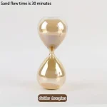 Vaso di sabbia dorato con flusso di sabbia di 30 minuti, simbolo di tempo e pazienza, perfetto come decorazione scientifica o oggetto da collezione.