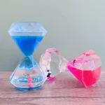 Orologio a clessidra decorativa in plastica trasparente con sabbia blu, rosa e trasparente, ideale come oggetto di decorazione scientifica e da scrivania.