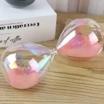 Vaso a clessidra decorativa con sabbia rosa e vetro trasparente, ideale come oggetto di design o decorazione scientifica per ambienti moderni e creativi.