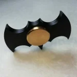 Oggetto decorativo a forma di pipistrello in metallo nero con palla dorata centrale, ideale come decorazione scientifica o da collezione.