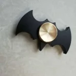 Pendente decorativo a forma di pipistrello con rotella centrale in metallo, ideale come decorazione scientifica o oggetto di design.