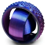 Anello in titanio colorato con superficie testurizzata e design moderno, ideale come decorazione scientifica o accessorio di stile.