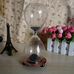 Orologio a Sabbia decorativo con base in metallo, ideale come oggetto di design e decorazione per ambienti moderni e studi scientifici.