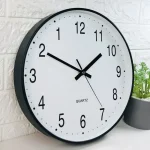Orologio da parete con numeri grandi e lancette nere, ideale per ambienti scientifici o studi. Movimento al quarzo preciso, facile da leggere e decorativo.
