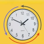 Orologio da parete con movimento circolare e frecce colorate blu, gialla e rossa, ideale come decorazione scientifica e oggetto educativo.