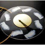 Orologio da parete decorativo con piume bianche e immagine della Torre Eiffel al centro, perfetto per ambienti scientifici o decorativi. Design elegante e originale, ideale come oggetto di arredamento.