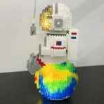 Modello di Lego di un astronauta con pianeta colorato e vulcano, decorazione scientifica originale e creativa.