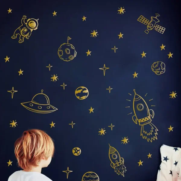 Decorazioni scientifiche a tema spazio per bambini, con astronavi, pianeti e stelle dorate su sfondo blu scuro.