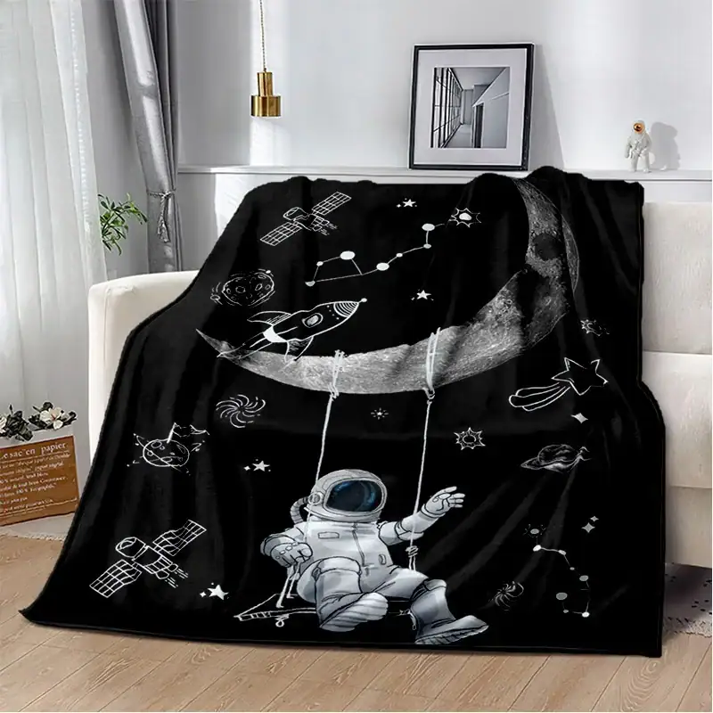 Piumone nero con stampa di astronauta, pianeti, stelle e navicelle spaziali, perfetto come decorazione per ambienti a tema scientifico o per gli appassionati di spazio e astronomia.