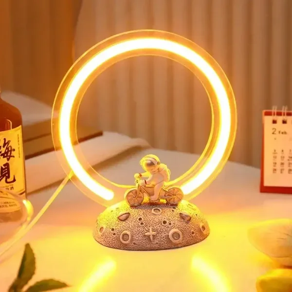 Lampada decorativa con anello luminoso e figura di bambino in bicicletta.