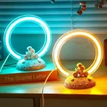 Anelli luminosi blu e gialli con figure di astronauti su basi rocciose, decorazioni scientifiche luminose per ambienti educativi o di intrattenimento.