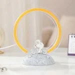 Lampada decorativa a forma di astronauta su bicicletta con anello luminoso giallo, perfetta come oggetto scientifico e decorativo.