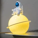 Decorazione luminosa con astronauta in orbita su pianeta giallo, perfetta come oggetto decorativo scientifico.