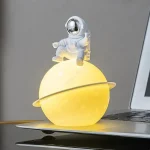 Modello di astronauta su pianeta giallo con anello, decorazione scientifica luminosa, oggetto decorativo per appassionati di spazio e scienza.
