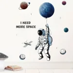 Astronauta con pallone che dice "I NEED MORE SPACE" tra pianeti e stelle, decorazione murale ispirata allo spazio e all'astronomia, perfetta per ambienti educativi o dedicati alla scienza.