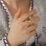 Anello decorativo con simboli scientifici e formule, indossato su una mano femminile. Perfetto come oggetto decorativo o regalo a tema scientifico.