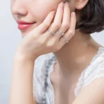 Donna con anelli decorativi a forma di strumenti scientifici, come microscopi e atomi, indossati come gioielli eleganti e originali.