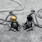 Collane con pendenti a forma di astronauta, uno con testa dorata e l'altro nera, in stile scientifico, perfette come decorazioni uniche e originali.