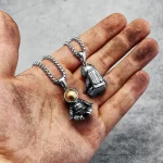 Collana con pendente a forma di astronauta e razzo, realizzata in metallo argentato, indossata su una mano sporca di terra, simbolo di esplorazione spaziale e avventura.