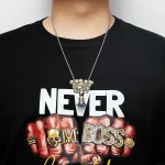 Collana con pendente a forma di teschio e scritta "BOSS" in stile audace, indossata da una persona con maglietta nera. Accessorio di moda ispirato al tema scientifico e decorativo.