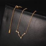 Collana con pendente a forma di V decorato con cristalli e catena dorata, elegante e raffinata, perfetta come regalo o accessorio di moda.