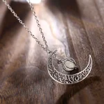 Collana con pendente a forma di luna e cristallo in argento, decorata con motivi intricati, ideale come gioiello decorativo e simbolico.