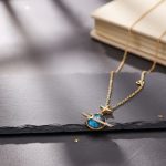 Collana decorativa con pendente a forma di pianeta e stella, realizzata in oro con dettagli in smalto blu, perfetta come oggetto decorativo o regalo originale.
