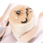 Orecchini Luna e Stelle in oro con dettagli in smalto nero e cristalli, perfetti come accessori decorativi e simbolici. Ideali per appassionati di astronomia e stile elegante.