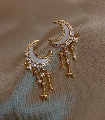 Orecchini pendenti a forma di luna e stelle con dettagli in cristallo.