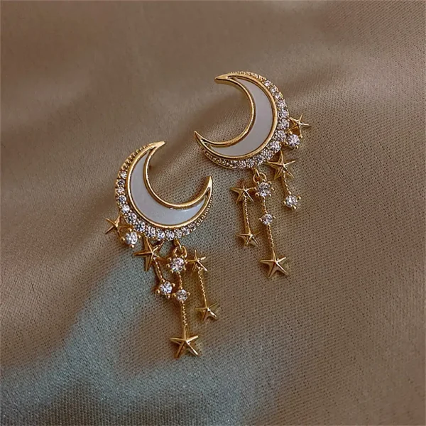 Orecchini pendenti a forma di luna e stelle con dettagli in cristallo.