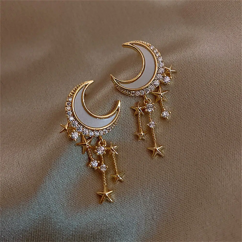 Orecchini pendenti a forma di luna e stelle con dettagli in cristallo.